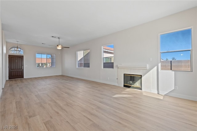 unfurnished living room featuring a fireplace, a ceiling fan, baseboards, visible vents, and light wood-style floors