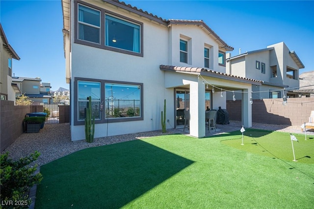 rear view of property with a fenced backyard, a tile roof, a patio, and stucco siding