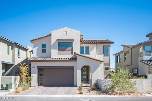 view of front of home with a fenced front yard, a tiled roof, an attached garage, decorative driveway, and stucco siding