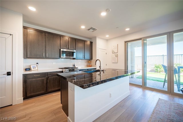 kitchen featuring visible vents, stainless steel microwave, light wood-style flooring, and a sink