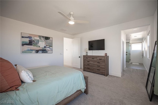 bedroom featuring baseboards, ensuite bathroom, a ceiling fan, and light colored carpet