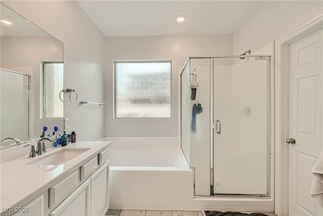 bathroom with a stall shower, a bath, and vanity