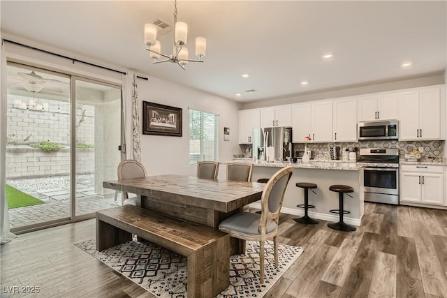 dining space with a notable chandelier, wood finished floors, and recessed lighting