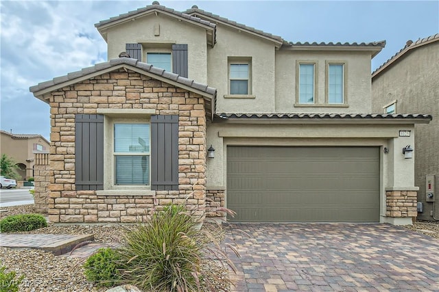 view of front of property featuring a garage, stone siding, decorative driveway, and stucco siding