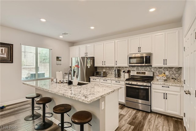 kitchen with stainless steel appliances, white cabinetry, and decorative backsplash