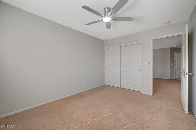 unfurnished bedroom featuring baseboards, ceiling fan, a closet, and light colored carpet