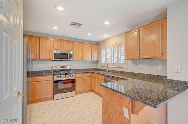 kitchen with visible vents, a peninsula, stainless steel appliances, a sink, and light tile patterned flooring