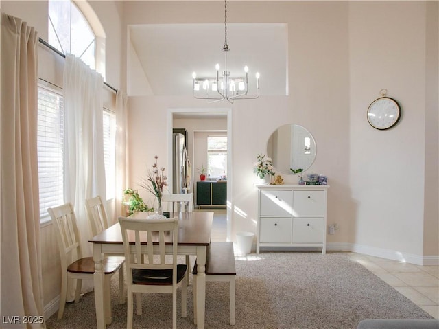 tiled dining room featuring a towering ceiling, an inviting chandelier, and baseboards