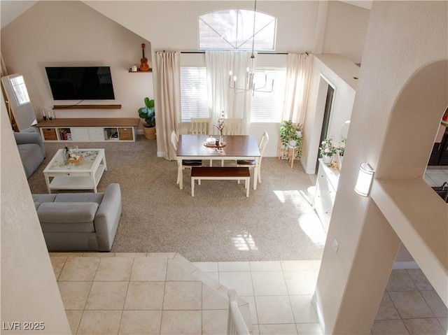 living area featuring carpet floors, a chandelier, high vaulted ceiling, and tile patterned floors