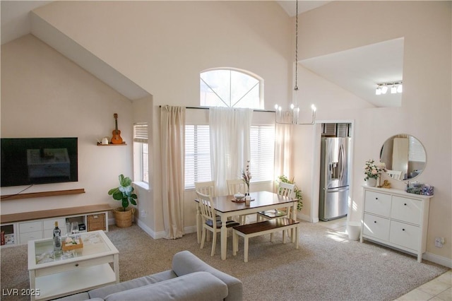 living area featuring light carpet, high vaulted ceiling, baseboards, and an inviting chandelier