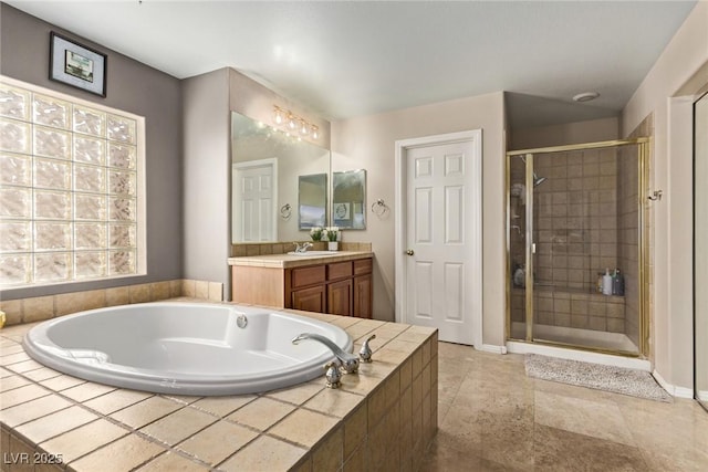 bathroom with a garden tub, vanity, baseboards, and a shower stall