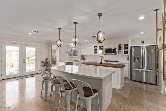 kitchen featuring a center island, visible vents, white cabinetry, tasteful backsplash, and appliances with stainless steel finishes