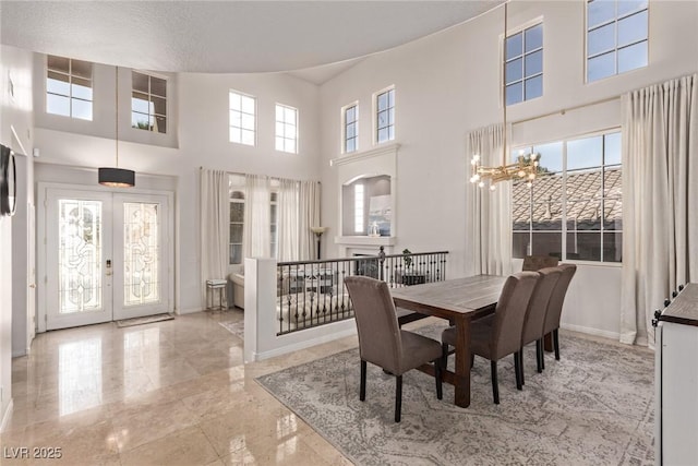 dining area featuring an inviting chandelier, french doors, a high ceiling, baseboards, and marble finish floor