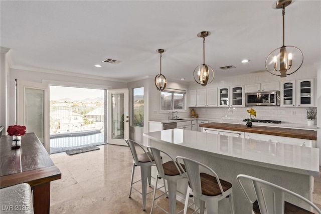 kitchen featuring stainless steel appliances, ornamental molding, visible vents, an inviting chandelier, and decorative backsplash