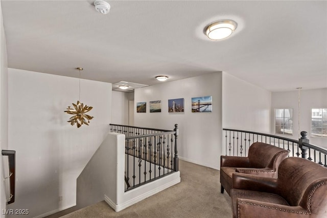 living area featuring an upstairs landing, baseboards, and carpet floors