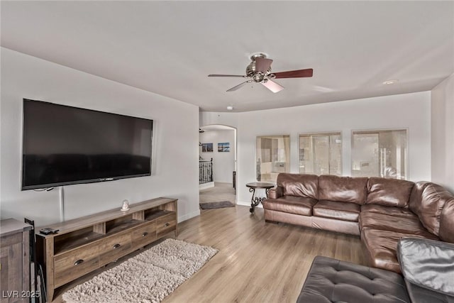 living room with baseboards, wood finished floors, a ceiling fan, and arched walkways