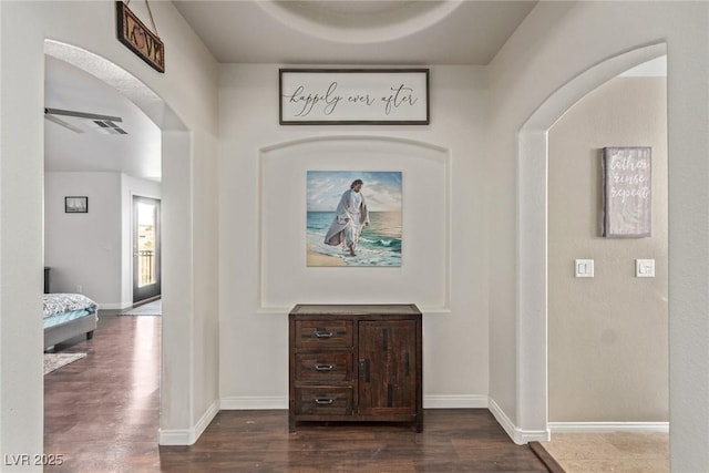 interior space with arched walkways, baseboards, and dark wood finished floors