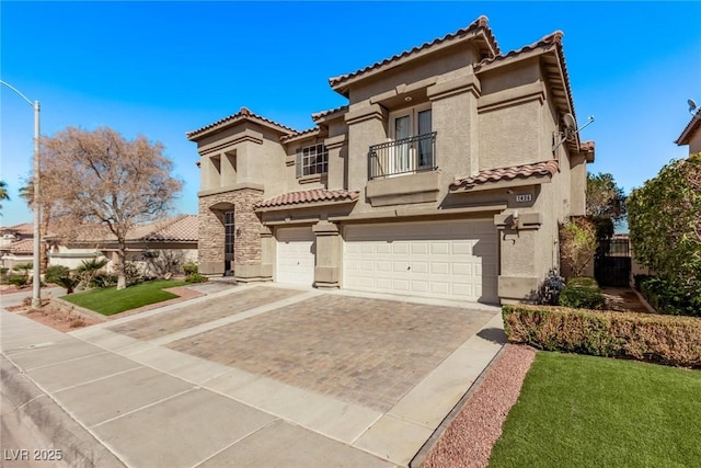 mediterranean / spanish home with an attached garage, a balcony, a tile roof, stucco siding, and decorative driveway