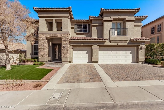 mediterranean / spanish-style home featuring decorative driveway, stucco siding, a balcony, a garage, and stone siding