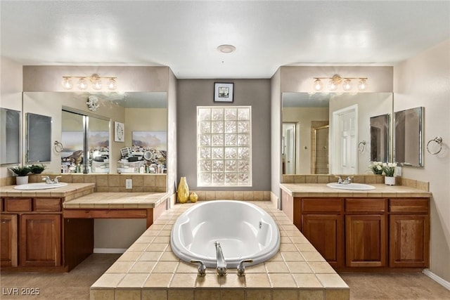 bathroom with a garden tub, a shower stall, two vanities, and a sink