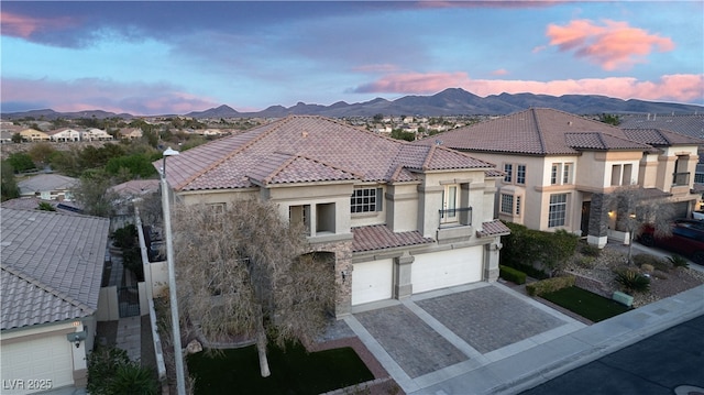 mediterranean / spanish home featuring an attached garage, a residential view, stucco siding, a tiled roof, and decorative driveway