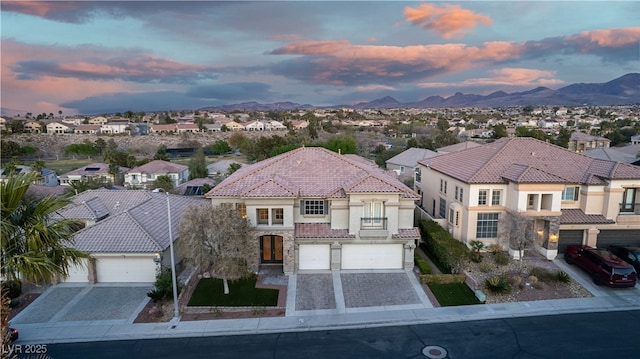 mediterranean / spanish house with a tiled roof, a mountain view, decorative driveway, stucco siding, and a residential view