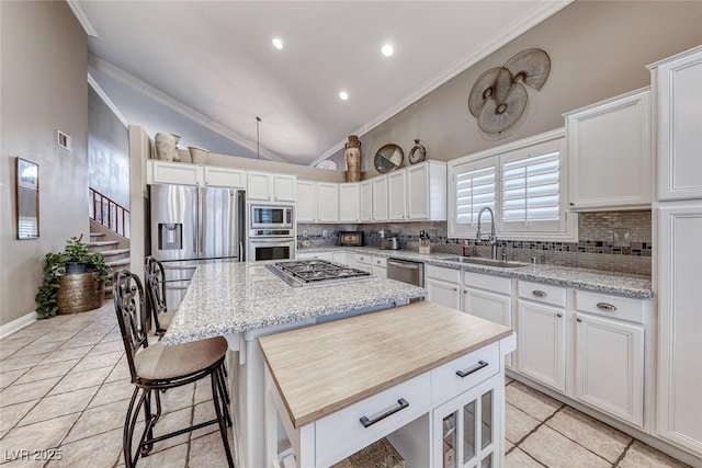 kitchen featuring tasteful backsplash, appliances with stainless steel finishes, ornamental molding, a sink, and a kitchen island