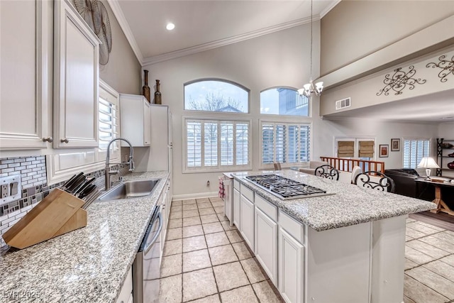 kitchen with ornamental molding, open floor plan, white cabinetry, and a sink