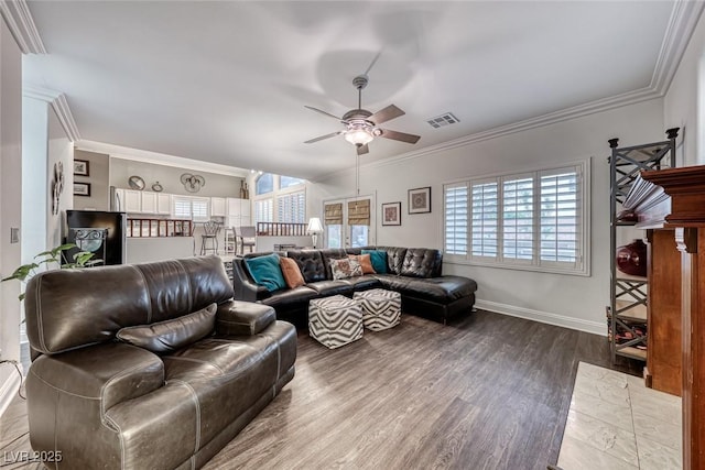 living area with dark wood finished floors, visible vents, ornamental molding, a ceiling fan, and baseboards