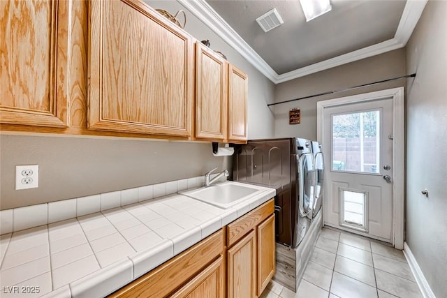 washroom with washer and clothes dryer, visible vents, cabinet space, ornamental molding, and a sink