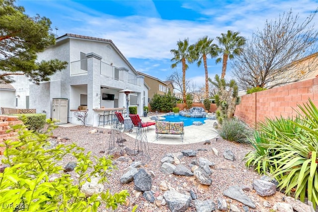 back of house with a fenced in pool, a patio, outdoor dry bar, a balcony, and a fenced backyard