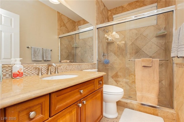 bathroom featuring vanity, backsplash, a shower stall, and toilet