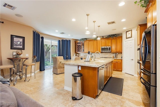 kitchen with visible vents, a center island with sink, appliances with stainless steel finishes, and tasteful backsplash