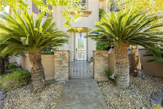 doorway to property with fence, a gate, and stucco siding