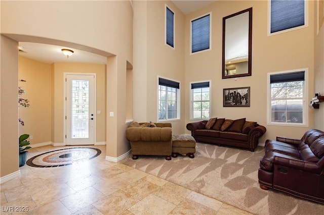 entryway featuring arched walkways, a towering ceiling, and baseboards