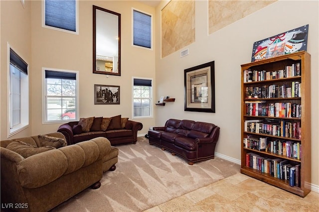 carpeted living area featuring a towering ceiling, visible vents, and baseboards