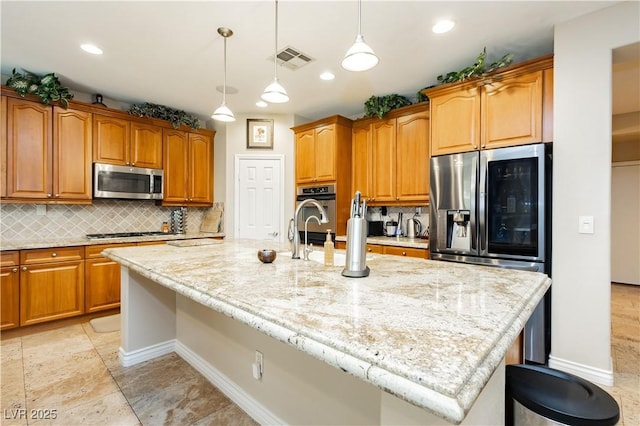 kitchen featuring a kitchen island with sink, visible vents, stainless steel appliances, and light stone counters