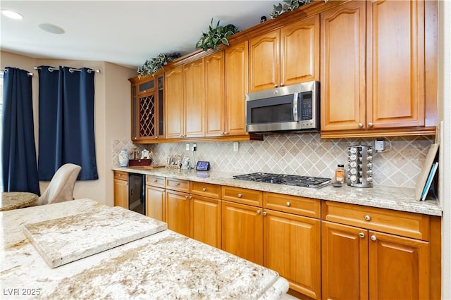 kitchen with light stone counters, glass insert cabinets, stainless steel appliances, and decorative backsplash