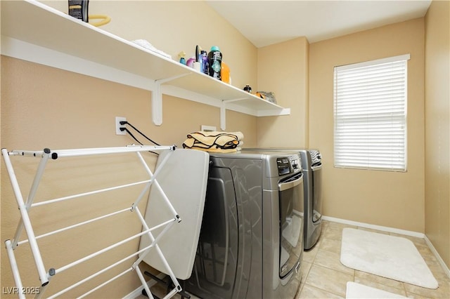 laundry area featuring laundry area, baseboards, washing machine and clothes dryer, and light tile patterned floors