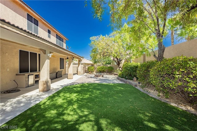 view of yard featuring an outdoor fire pit, a fenced backyard, and a patio