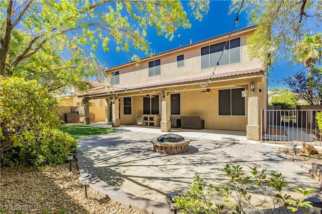 back of property featuring ceiling fan, a patio, a fire pit, fence, and stucco siding