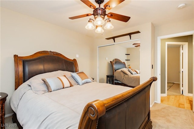 bedroom featuring light carpet, ceiling fan, baseboards, and a closet