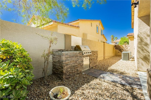 view of property exterior featuring a tile roof, stucco siding, area for grilling, cooling unit, and a fenced backyard