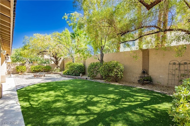 view of yard featuring a fenced backyard, a fire pit, and a patio