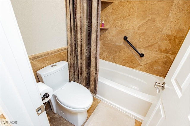 full bathroom with toilet, a wainscoted wall, shower / bath combination with curtain, and tile walls