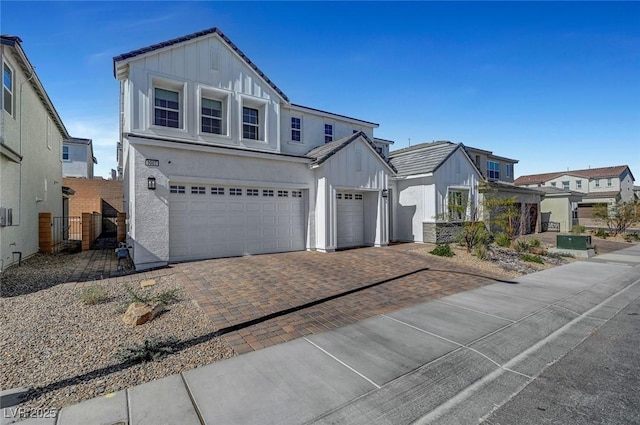 view of front of home featuring an attached garage, decorative driveway, fence, and board and batten siding