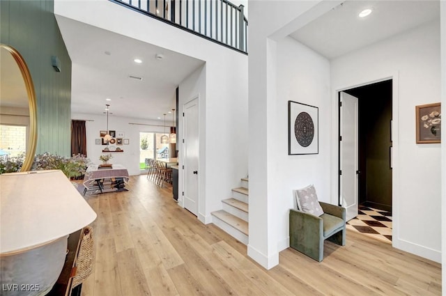 hallway featuring stairs, light wood finished floors, and recessed lighting