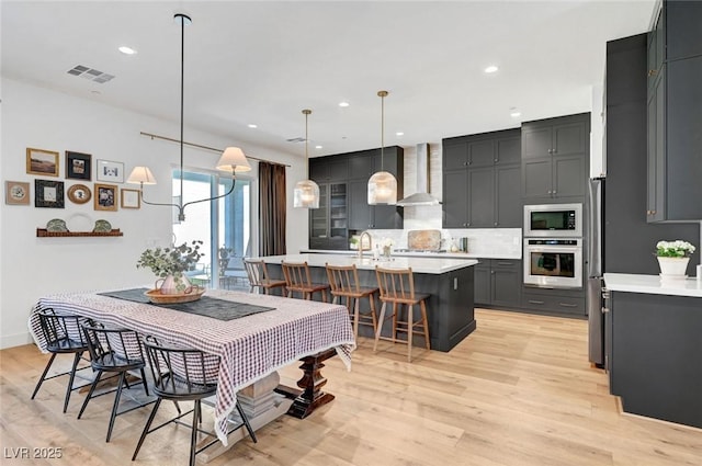 dining area featuring baseboards, light wood finished floors, visible vents, and recessed lighting