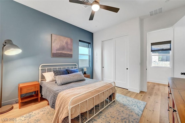 bedroom with multiple windows, light wood-type flooring, a closet, and visible vents