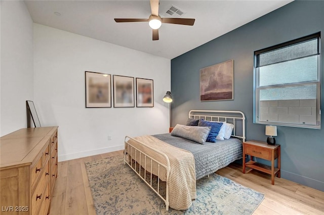 bedroom featuring light wood-style floors, visible vents, baseboards, and a ceiling fan